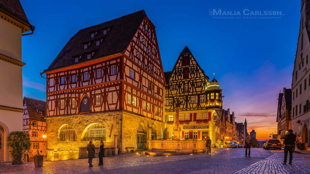 Rothenburg ob der Tauber der weltbekannte St. Georgs Brunnen am Marktplatz zur blauen Stunde mit knallorangefarbenen Sonnenuntergang im Hintergrund