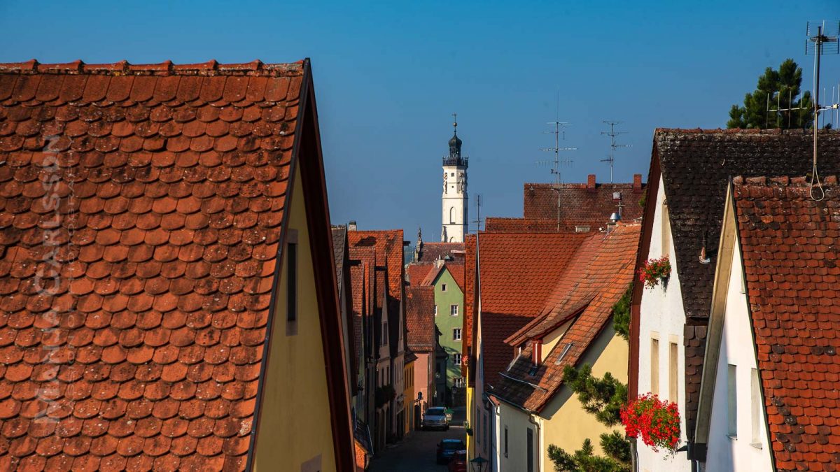 Rothenburg ob der Tauber - Blick auf die roten Dächer von Rothenburg - am Ende der Gasse steht ein weißer Turm